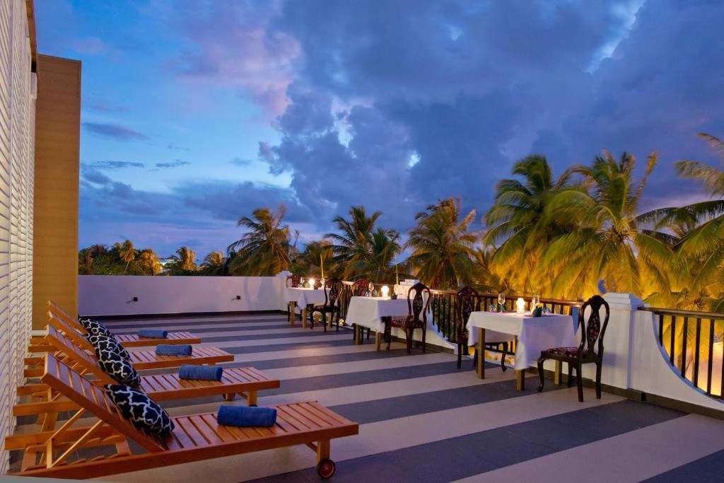 Rooftop terrace with sun loungers and dining tables at sunset, Crystal Sands Maafushi